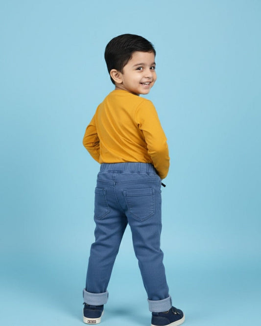 Child wearing a mustard yellow shirt and blue pants on a light blue background