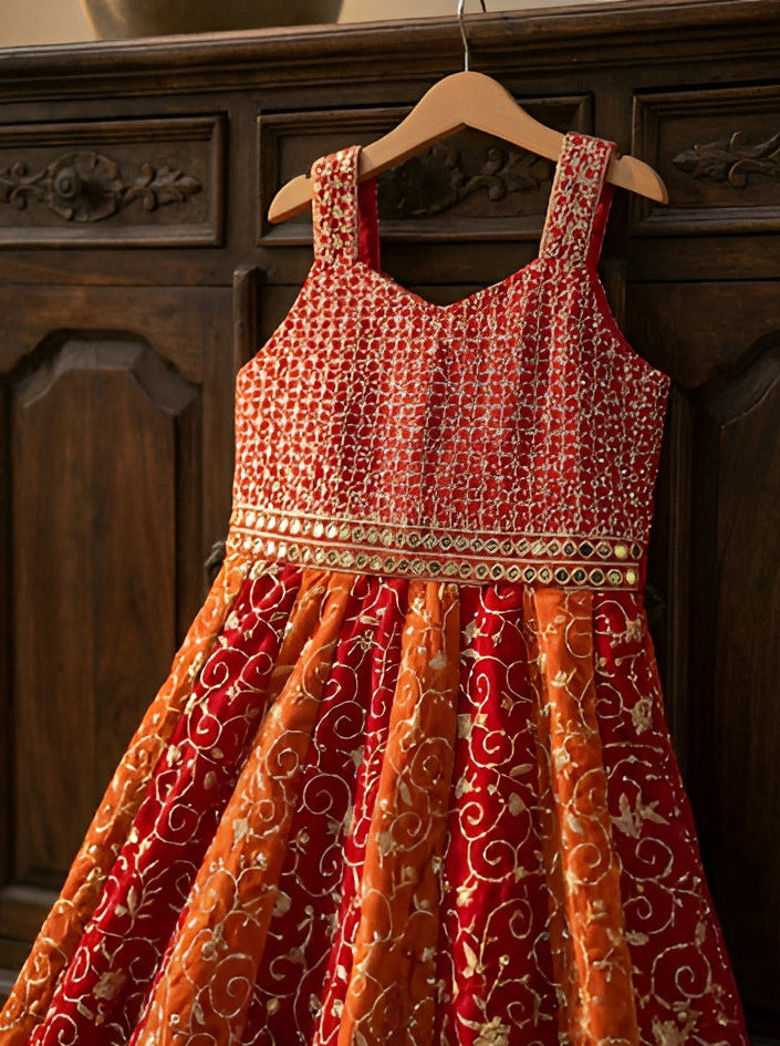 Red and orange patterned dress on a wooden hanger against a dark wooden background