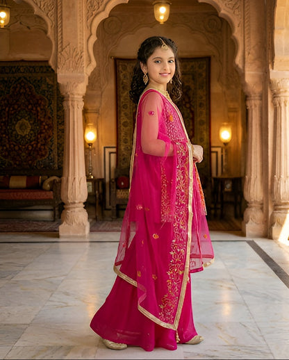 Woman in a bright pink traditional outfit standing in an ornate hall.