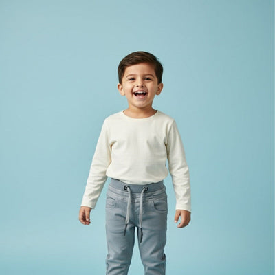 Child wearing a white long-sleeve shirt and light blue pants against a light blue background