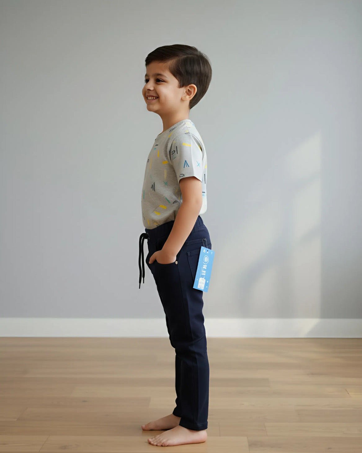 Child standing on a wooden floor with a plain gray wall background