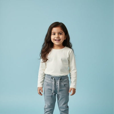 Young girl wearing a white shirt and light blue pants on a light blue background
