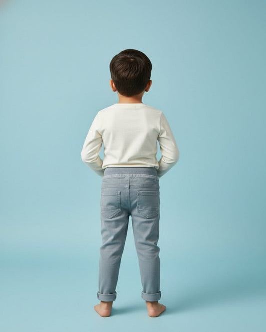 Child wearing a white shirt and light blue jeans against a light blue background
