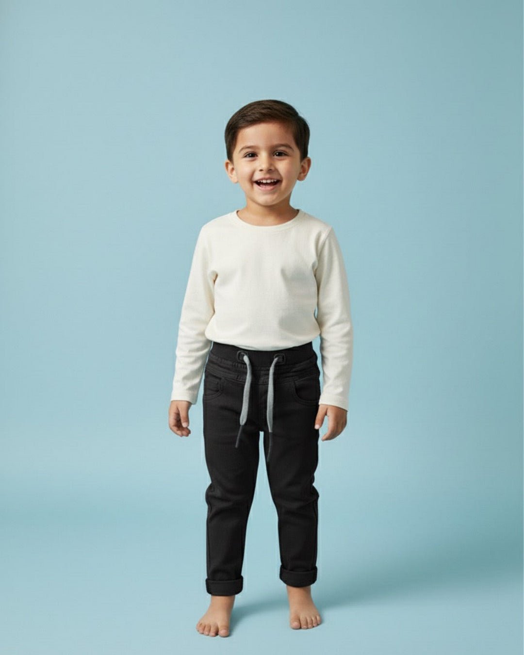 Child wearing a white sweater and black pants on a light blue background