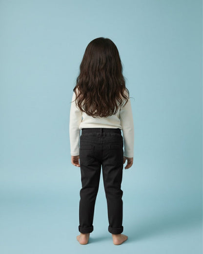Child wearing black pants and a light-colored top on a light blue background